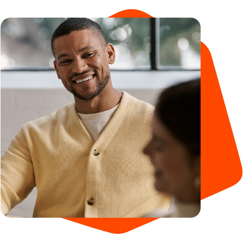 Black man in a yellow sweater smiling at a woman